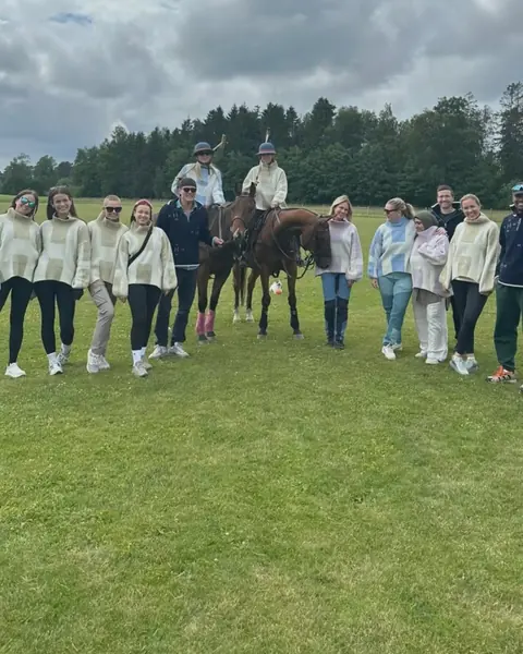 Gruppe gjester sammen med hestene på banen